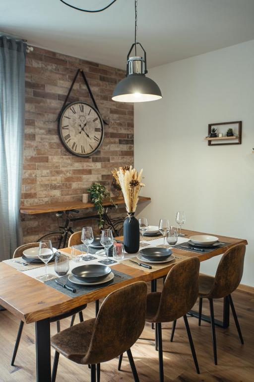 a dining room table with chairs and a clock on a wall at The Brick 194, 7 posti letto in Udine