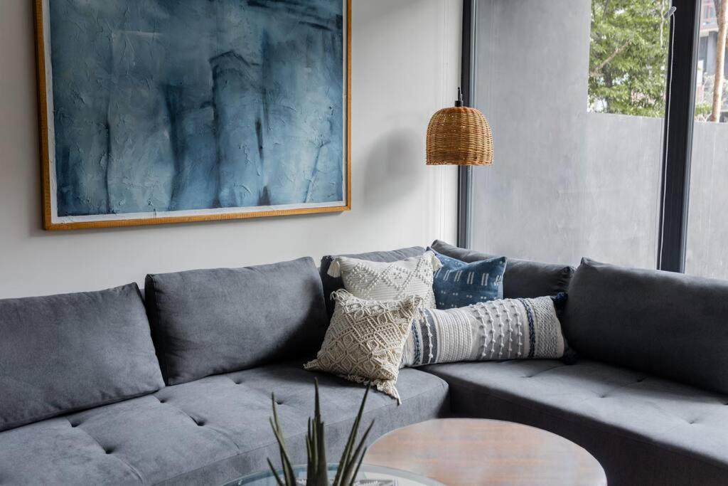 a living room with a gray couch and a table at 2BR Designer's Pad Private Pool Closest to Beach in Tulum