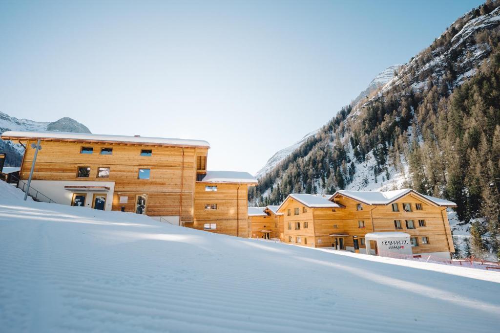 a building in the snow next to a mountain at SWISSPEAK Resorts Zinal in Zinal