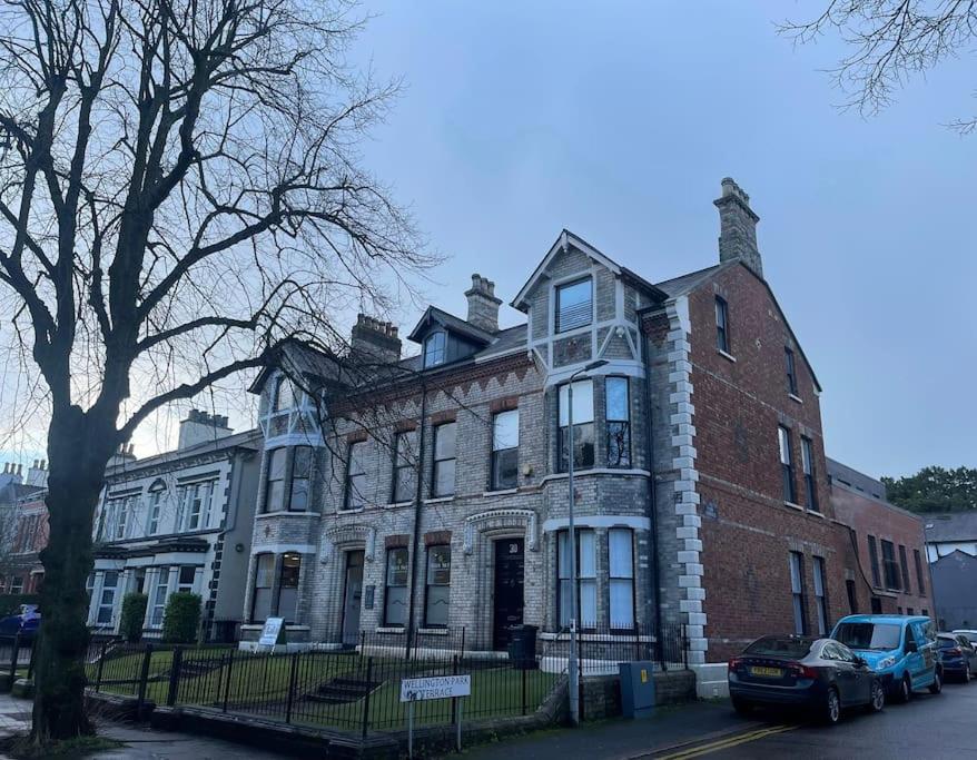 een groot bakstenen gebouw met auto's geparkeerd voor het bij Townhouse in Belfast in Belfast