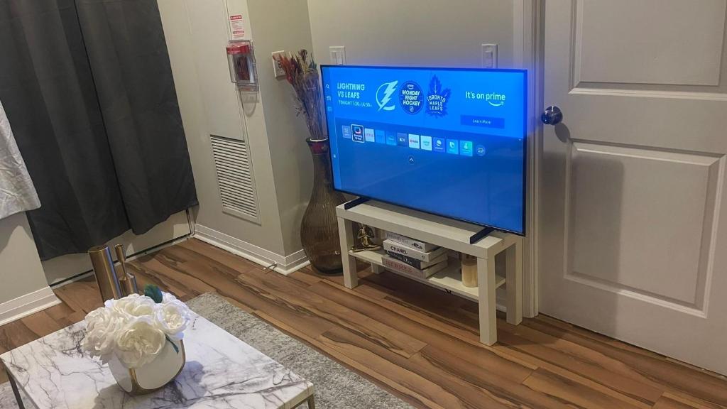 a flat screen tv sitting on a stand in a living room at Serene Queen Room Shared Unit in Mississauga