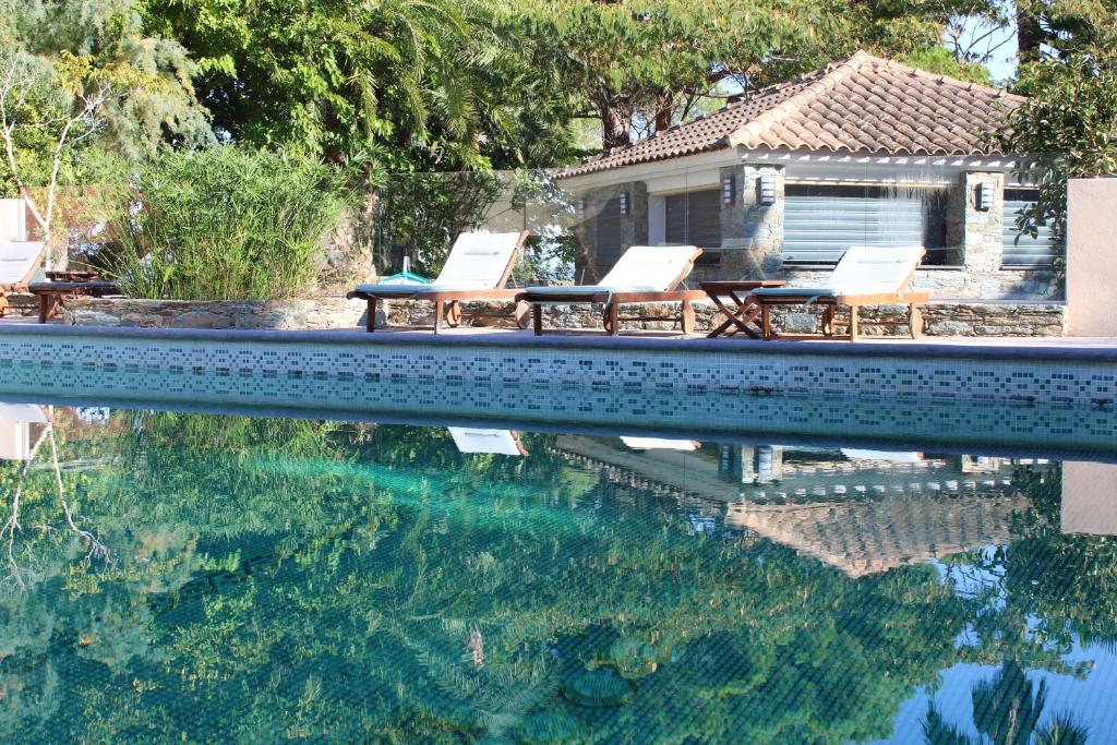 a swimming pool with two chairs and a house at Résidence Fior di Rena in Saint-Florent