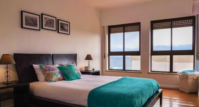 Un dormitorio con una cama grande con dos ventanas. en Populo Beach Apartment, en São Roque