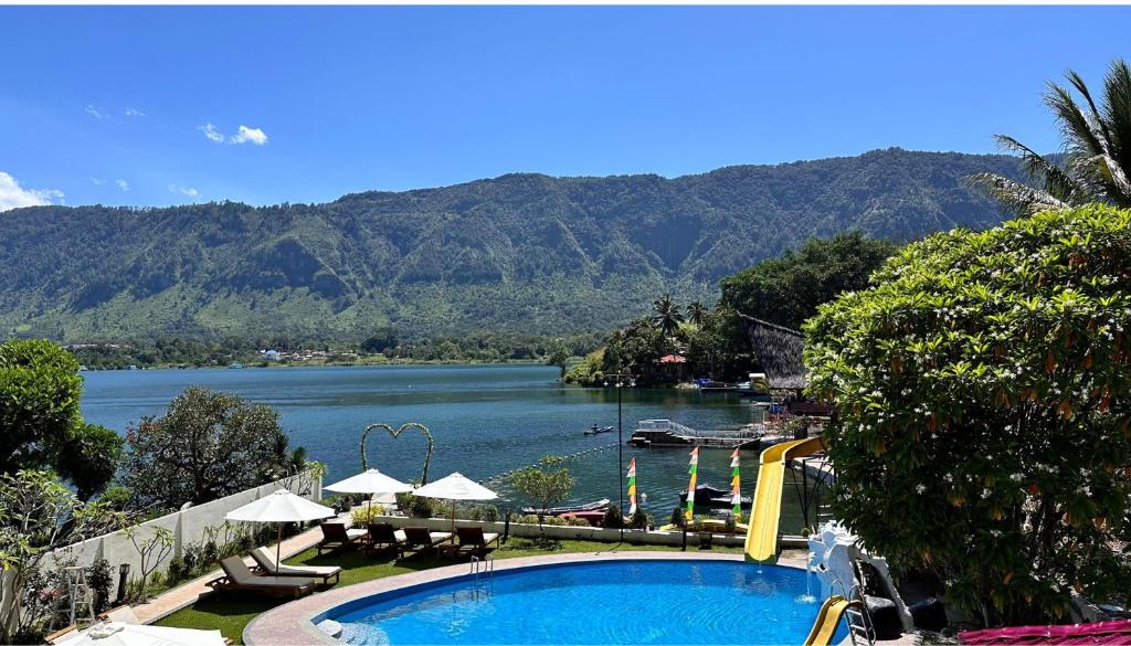 a swimming pool with a view of a river and mountains at Zoé’s Paradise Waterfront Hotel in Tuktuk Siadong