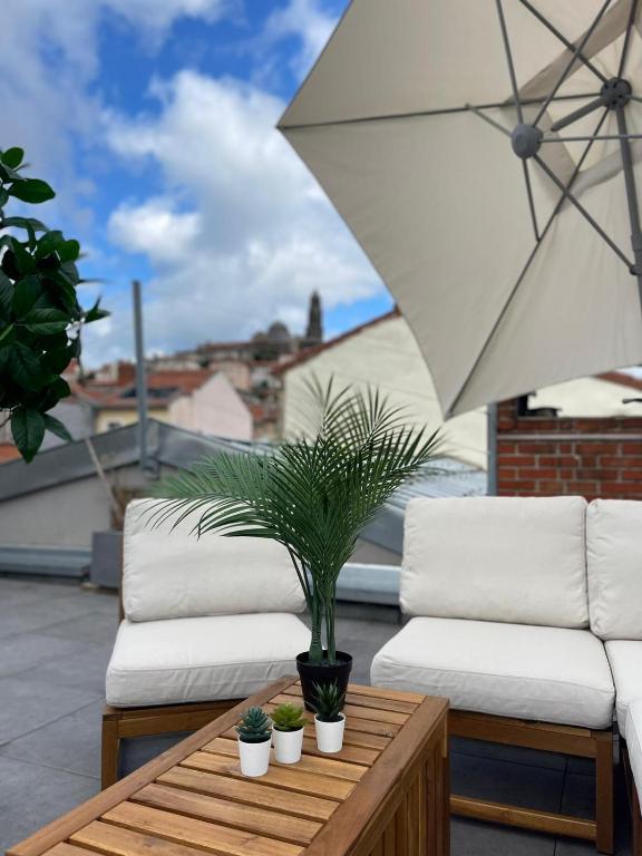 a patio with two white couches and a table with a plant at Rooftop d'exception au Cœur du Puy-en-Velay in Le Puy en Velay
