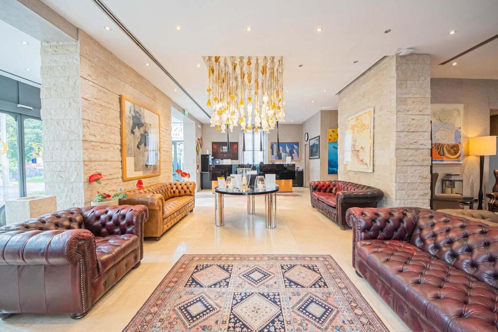 a living room with leather furniture and a chandelier at Century Hotel in Parma