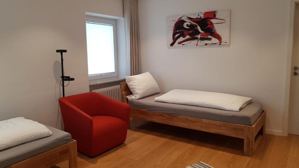 a room with two beds and a red chair at Ferienhaus Krone in Schliengen