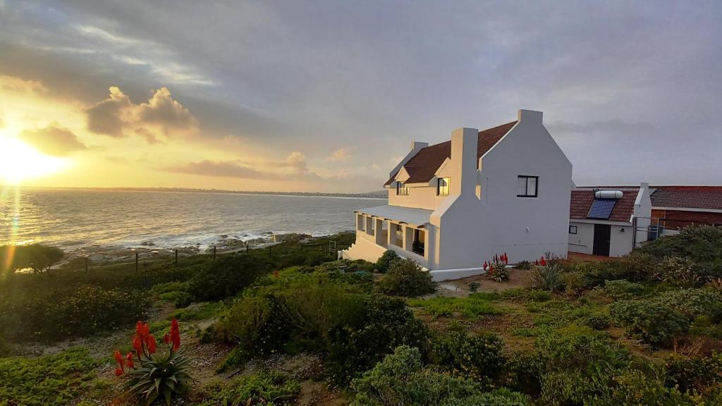 a white house on a hill with the ocean at Whale Watch Cottage in St Helena Bay