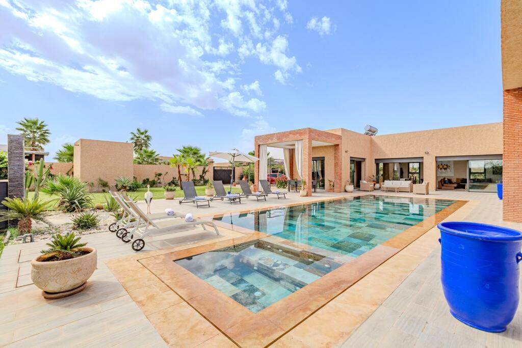 une grande piscine avec des chaises et un bâtiment dans l'établissement villa Zina, Élégance et luxe,piscine & jacuzzi, à Marrakech