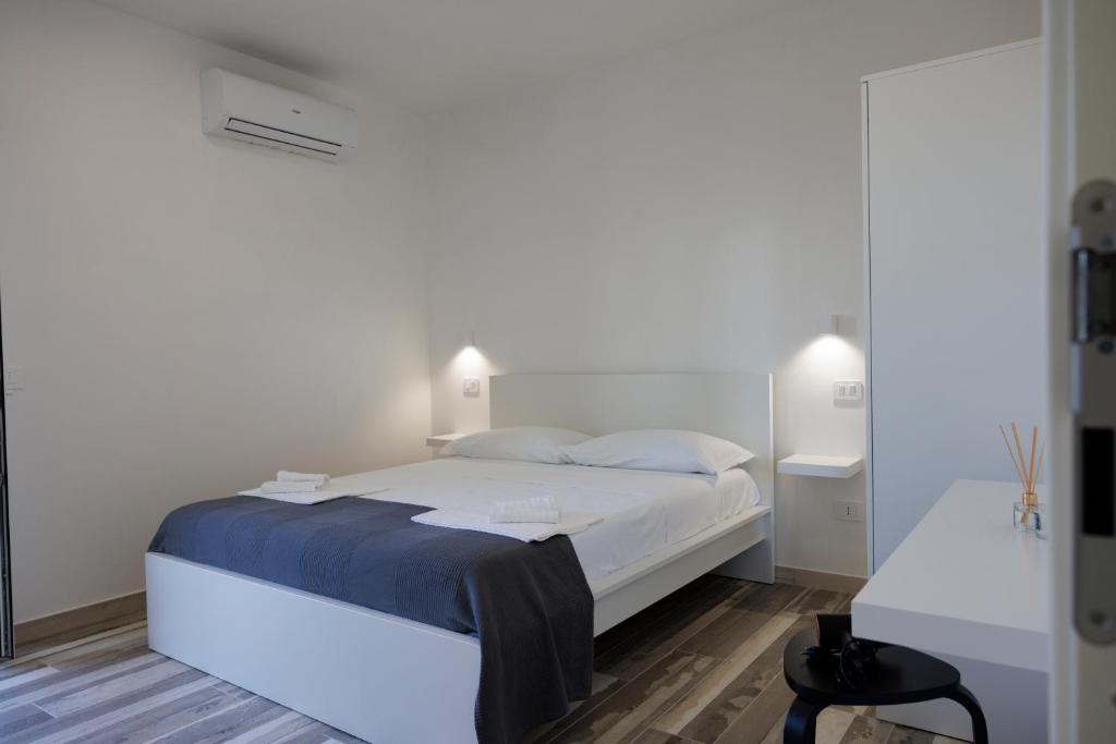 a white bedroom with a large bed and a table at Essentia Rooms & Relax in Vasto