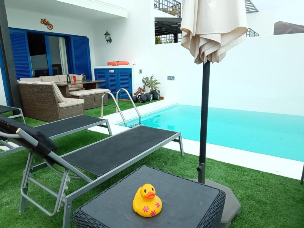 żółta gumowa kaczka siedząca na stole obok basenu w obiekcie Villa Erimar w mieście Playa Blanca