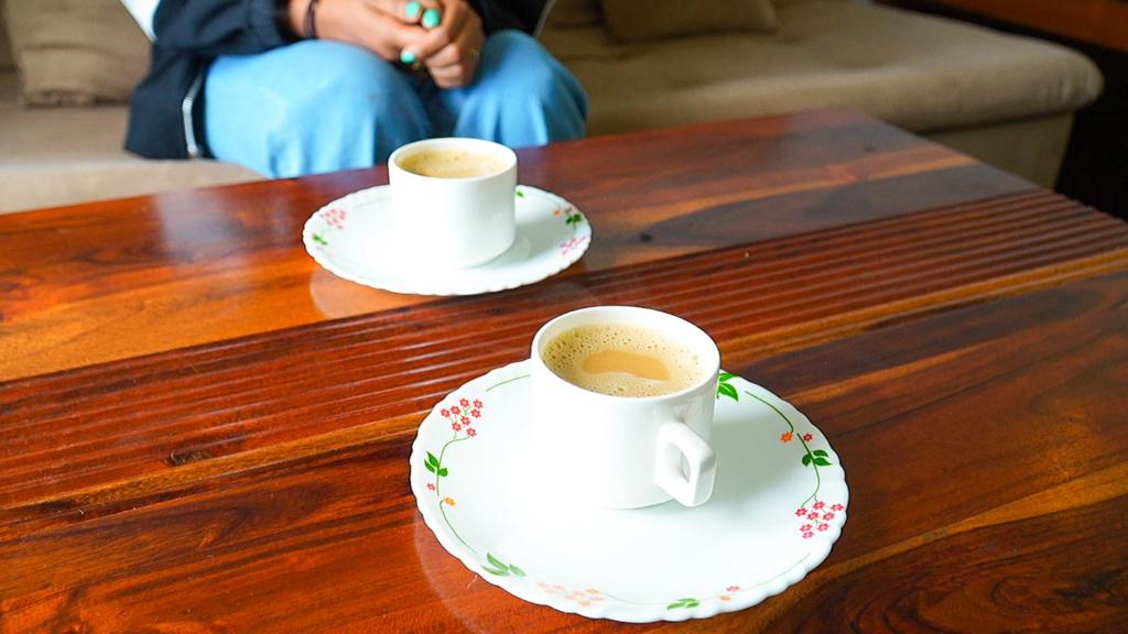 two cups of coffee sitting on a wooden table at HappyHuts at Green valley view in Kodaikānāl