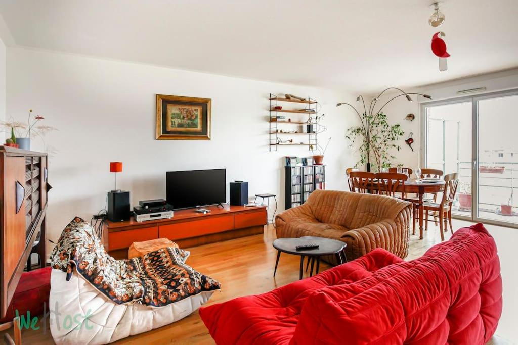 un salon avec un canapé rouge et une table dans l'établissement Brunhes Toulouse - CI - Spacieux 3 chambres Pkg Métro St Cyprien, à Toulouse