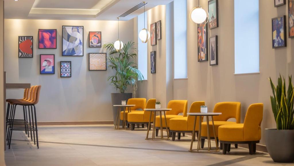 a waiting room with yellow chairs and tables at Maldron Hotel Brighton City Centre in Brighton & Hove