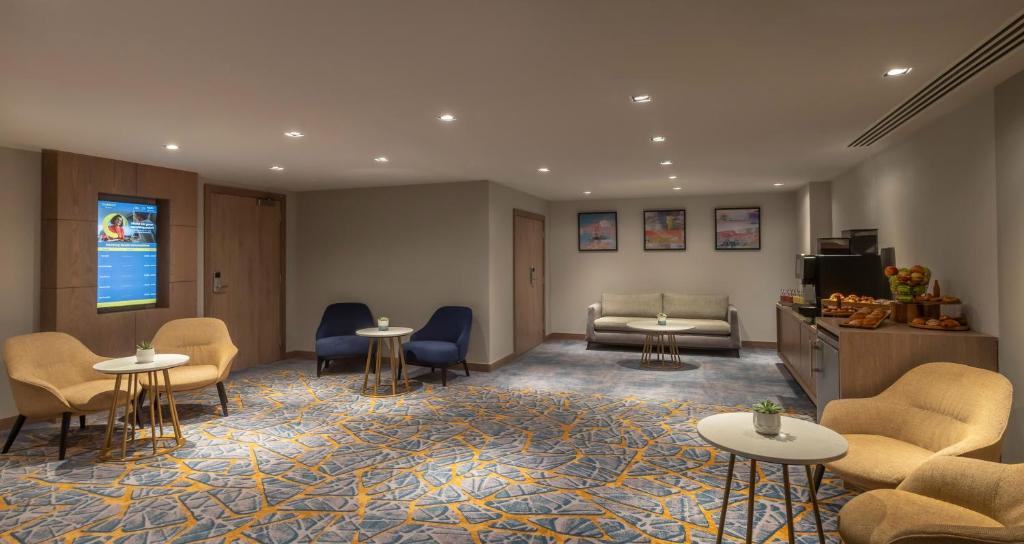 a waiting room with chairs and a couch and tables at Maldron Hotel Brighton City Centre in Brighton & Hove