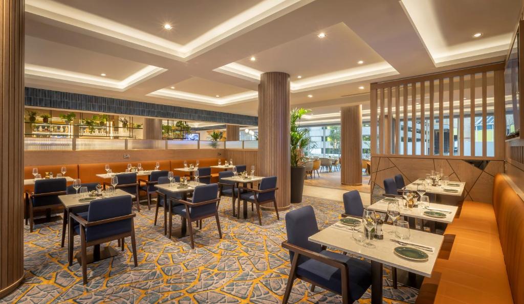 a dining room with tables and chairs in a restaurant at Maldron Hotel Brighton City Centre in Brighton & Hove