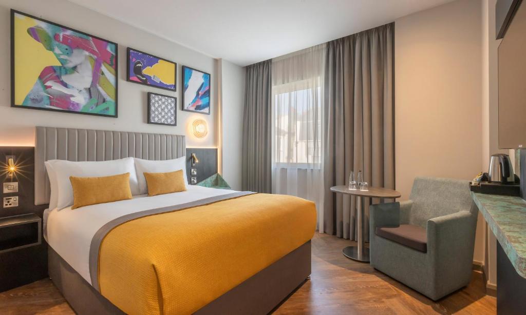 a hotel room with a bed and a chair at Maldron Hotel Brighton City Centre in Brighton & Hove