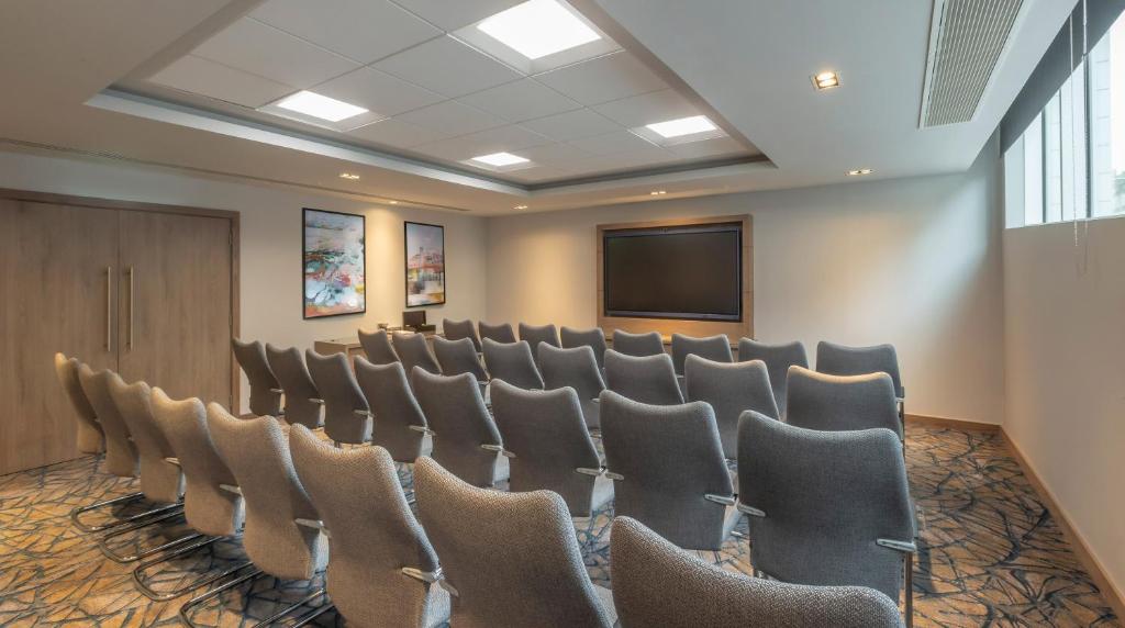 a conference room with chairs and a screen at Maldron Hotel Brighton City Centre in Brighton & Hove