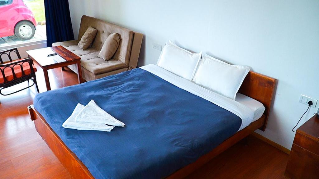 a bedroom with a large bed with a blue blanket at HappyHuts at Green valley view in Kodaikānāl