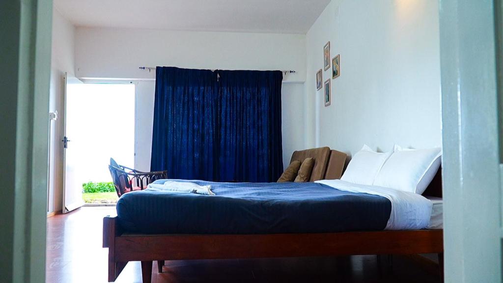 a bedroom with a bed with blue sheets and a window at HappyHuts at Green valley view in Kodaikānāl