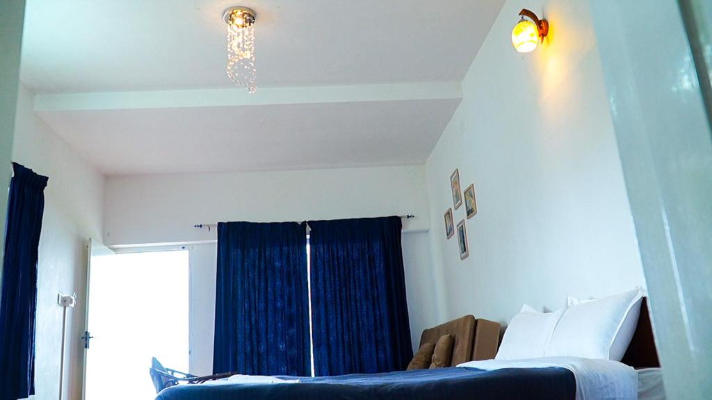 a bedroom with a blue bed and a chandelier at HappyHuts at Green valley view in Kodaikānāl