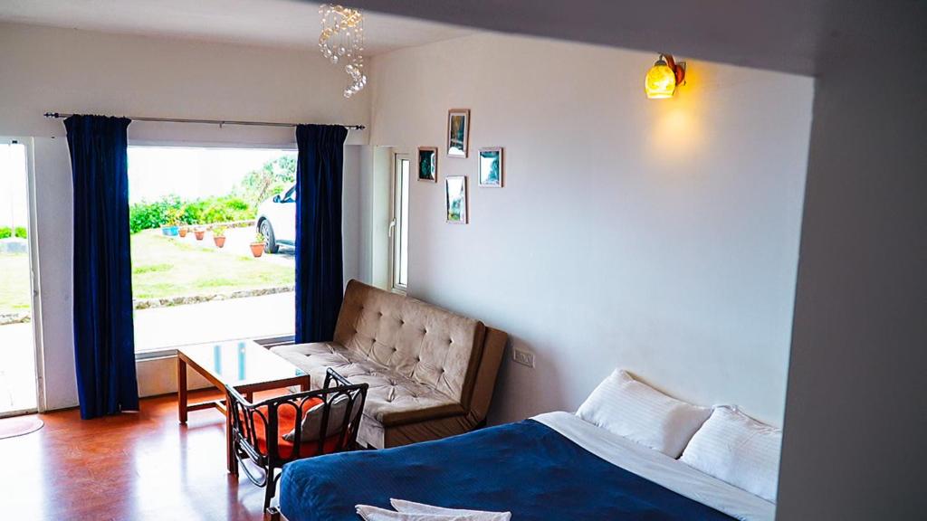 a bedroom with a bed and a table and a couch at HappyHuts at Green valley view in Kodaikānāl