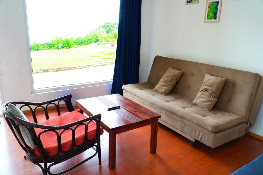 a living room with a couch and a table at HappyHuts at Green valley view in Kodaikānāl