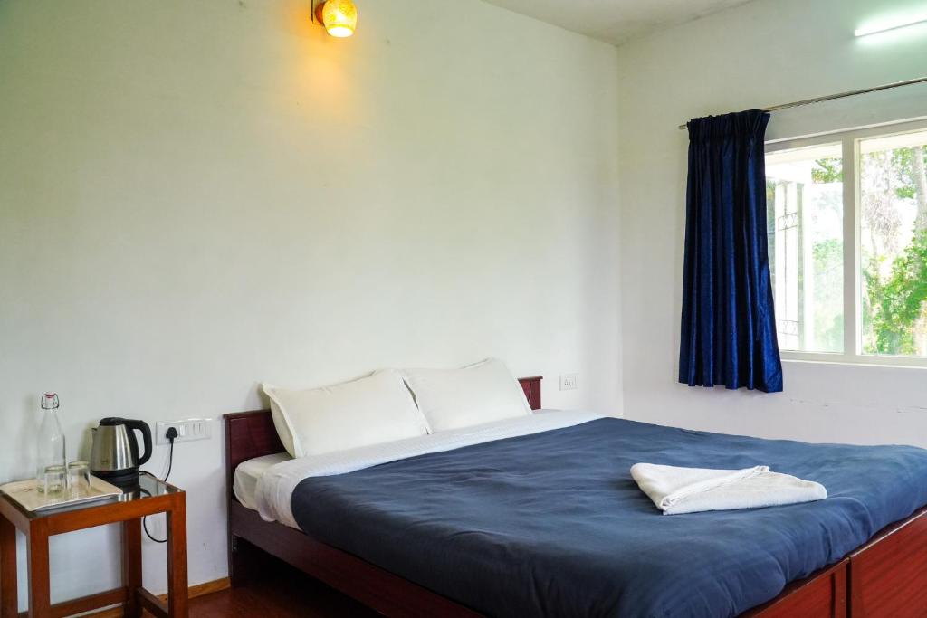 a bedroom with a bed with a blue blanket and a window at HappyHuts at Green valley view in Kodaikānāl