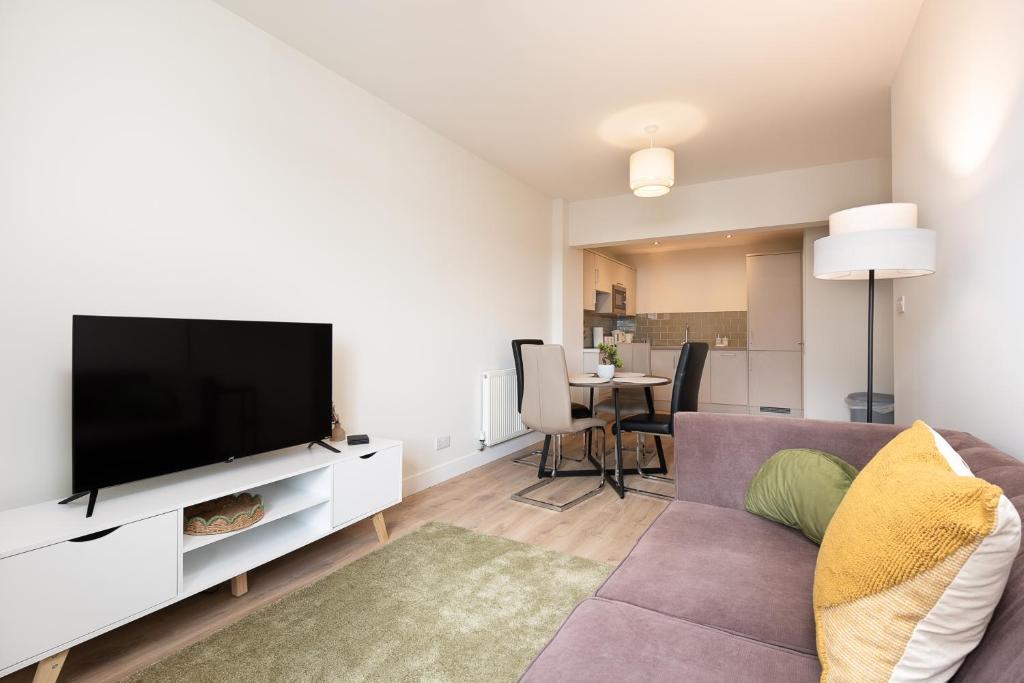 Una sala de estar con un sofá y un televisor de pantalla plana. en Unique 2 Bedroom Flat in Bicester, en Bicester