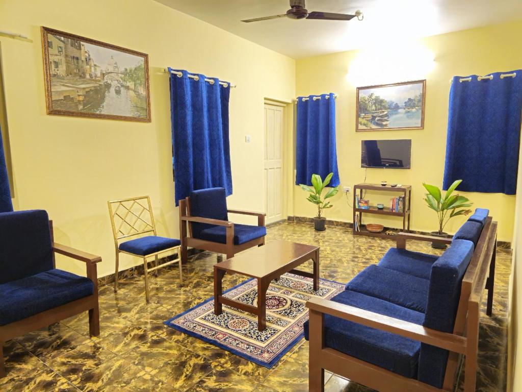 a living room with blue furniture and blue curtains at Casa de Bella in Candolim