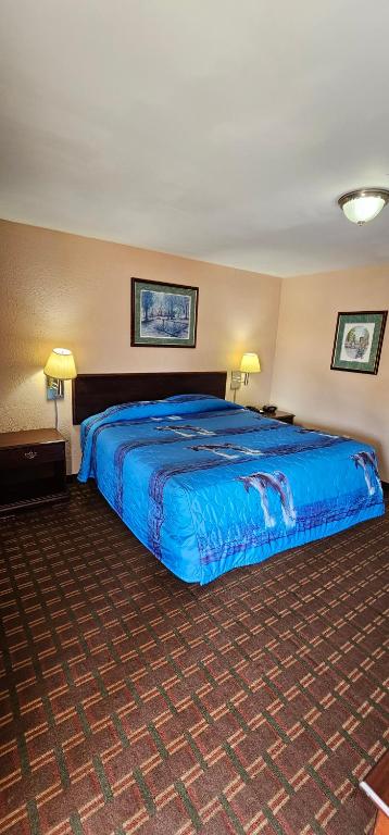 un grande letto in una camera d'albergo con lenzuola blu di Mount Laurel Motel a Hazleton