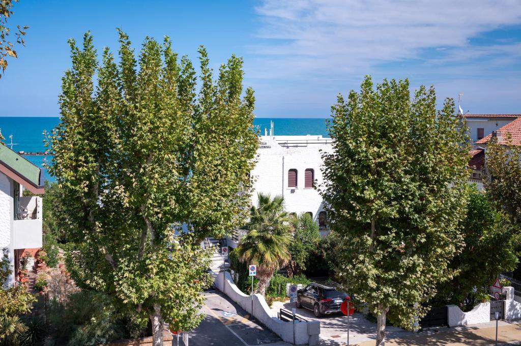 a white building with trees in front of the ocean at Desdemona in Francavilla al Mare