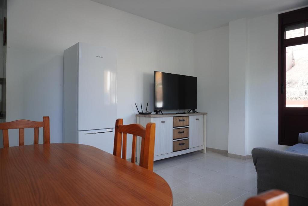 Una sala de estar con una mesa y un televisor sobre un mueble. en Holiday House La Noria, en San Sebastián de la Gomera