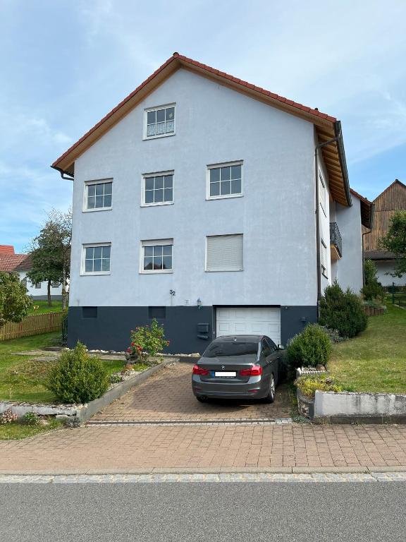 a car parked in front of a white house at Ferienwohnung zur Langen Meile in Kalteneggolsfeld