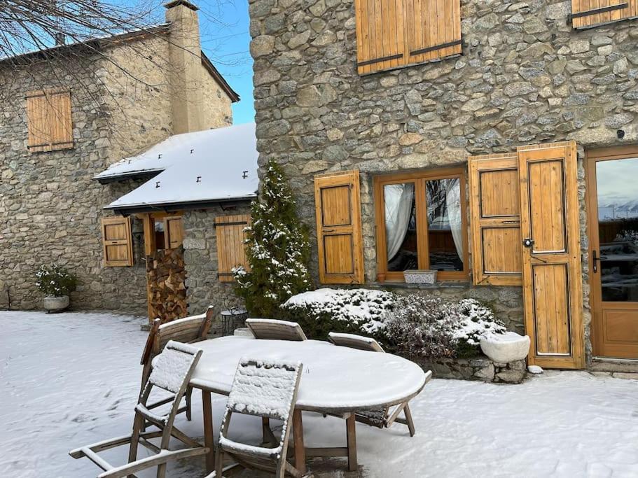 une table et des chaises dans la neige devant un bâtiment dans l'établissement Lujoso Refugio Tradicional de Montaña, à Font-Romeu-Odeillo-Via