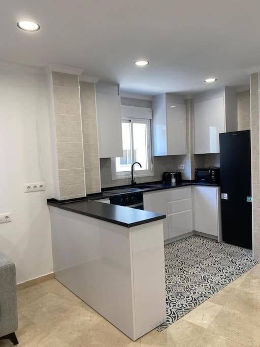 a kitchen with white cabinets and a black counter top at Edifico Mañez Primero- Nuevo, 10 minutos Gibraltar in La Línea de la Concepción