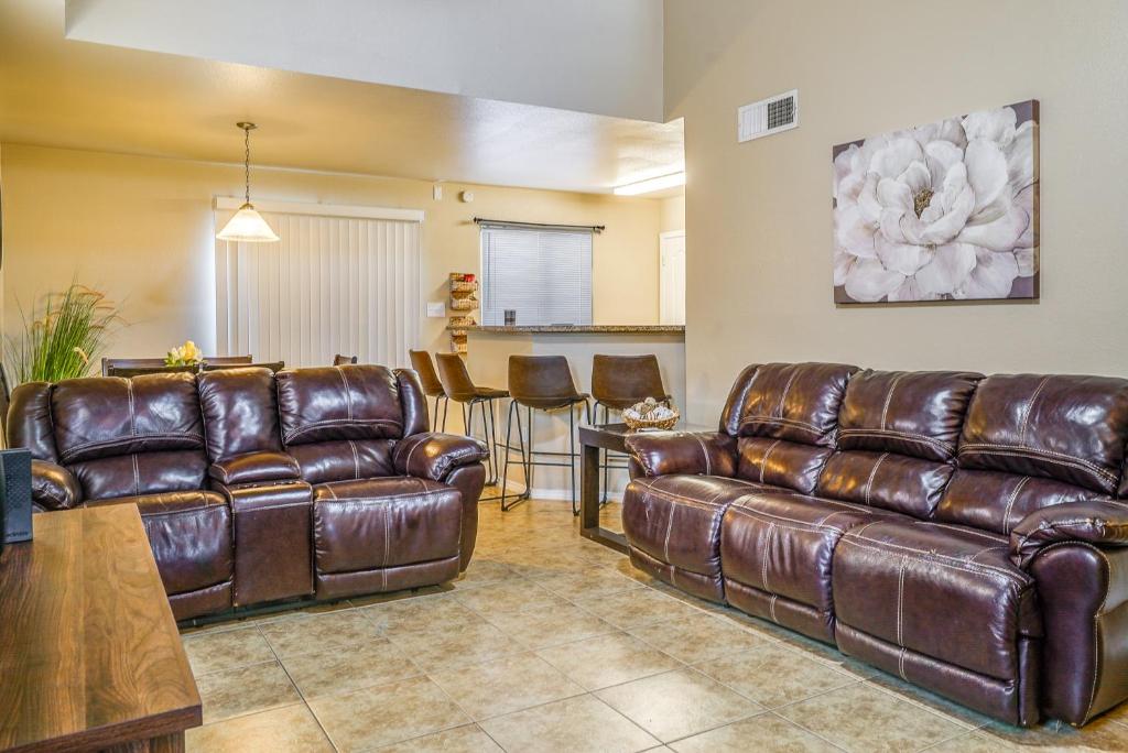 a living room with leather couches and a table at Sunny El Paso Home with Private Yard! in Homestead Meadows South