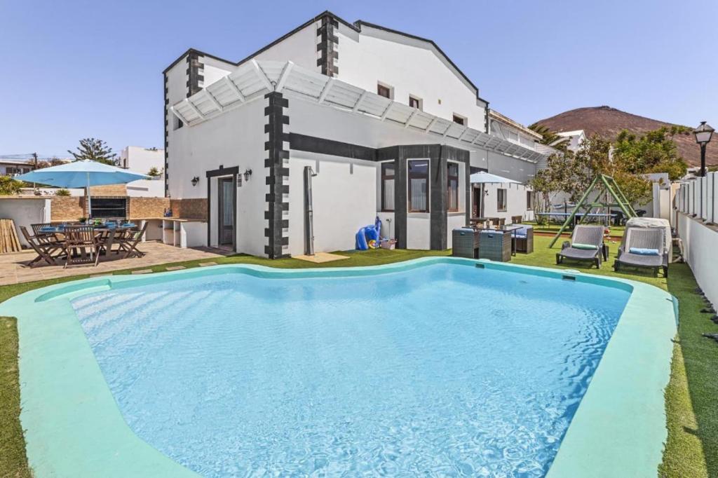 a villa with a swimming pool in front of a house at Villa Palacios Herrero in Tahiche