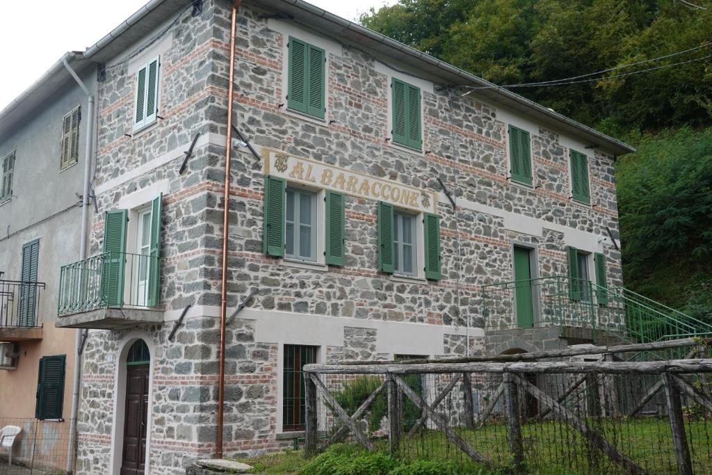 an old stone building with green shuttered windows at La Foresteria della Beppa in Zeri