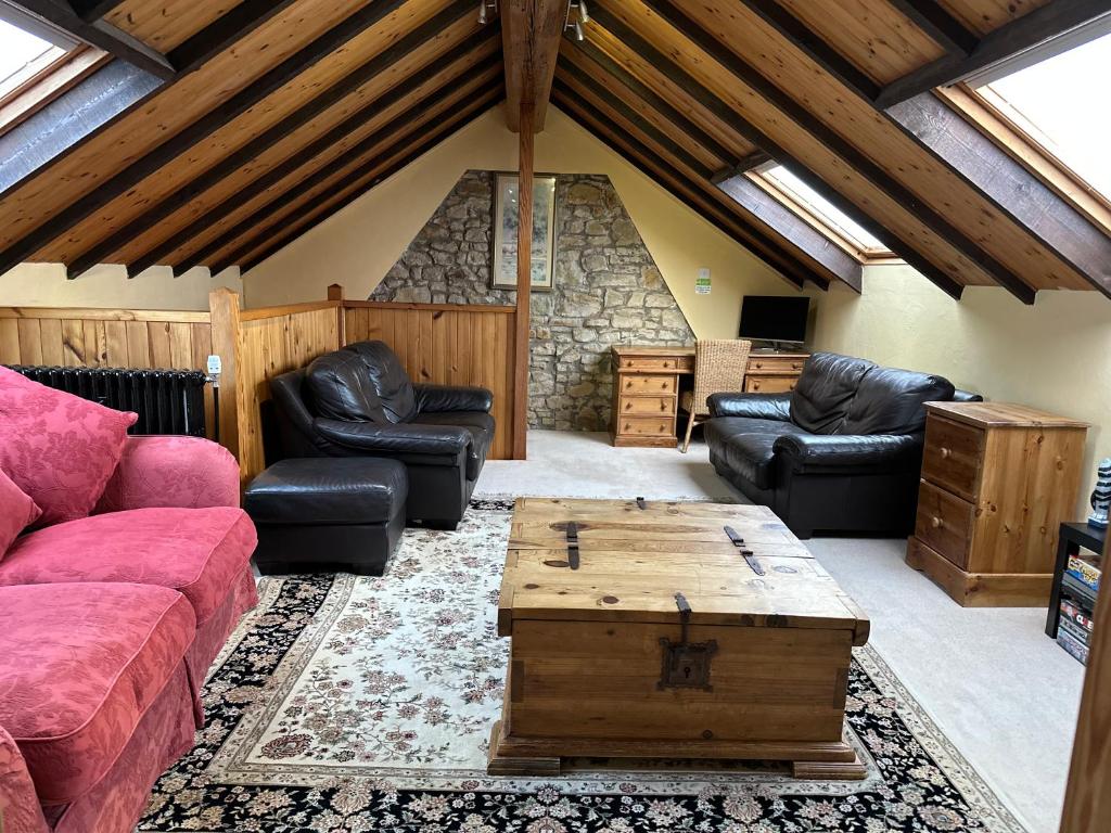 a living room with leather furniture and a stone wall at The Old Vicarage in Berwick-Upon-Tweed