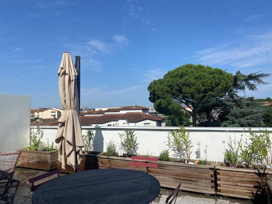 - une terrasse avec une table et un parasol dans l'établissement Dassaut - Toulouse - CI - 2 pièces spacieux avec grande terrasse et vue dégagée, à Toulouse
