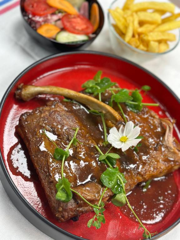 a red plate of food with meat and a flower on it at La Différence in Vichten