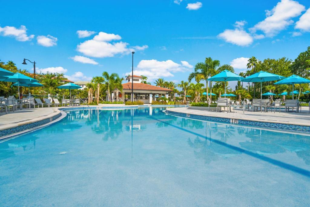una piscina en un complejo con sombrillas azules en Gorgeous Townhome w FREE Resort Access, en Orlando