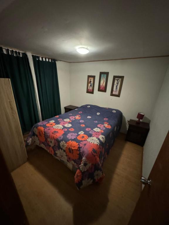 a bedroom with a bed with a floral comforter at ripamontilodge in Coquimbo