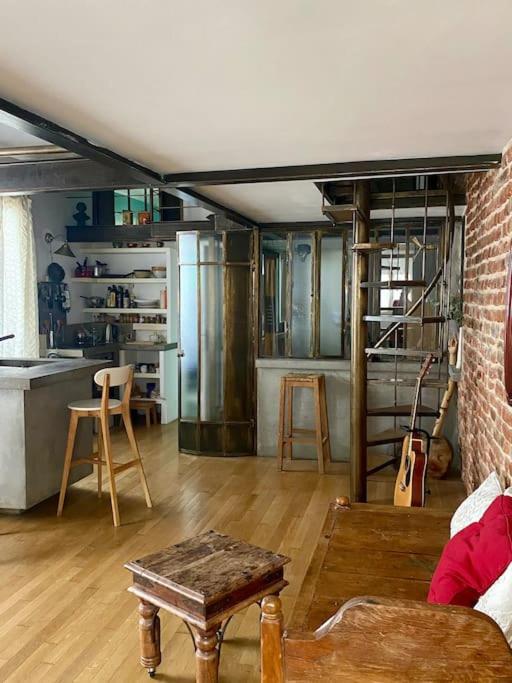 un salon avec une table et une cuisine dans l'établissement Logement de charme type loft parisien, à Bagnolet