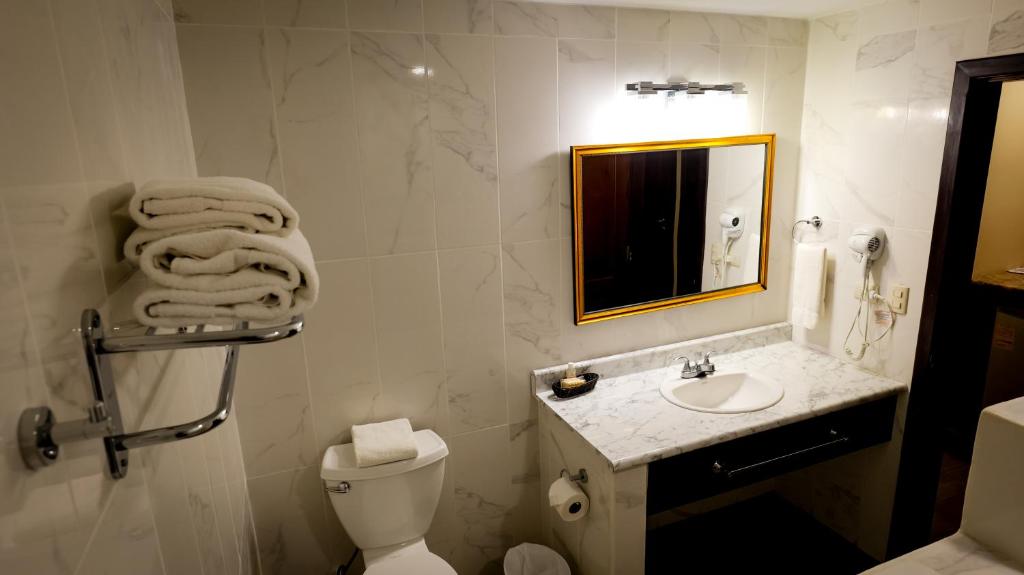 a bathroom with a toilet and a sink and a mirror at La Ensenada Beach Resort in Tela