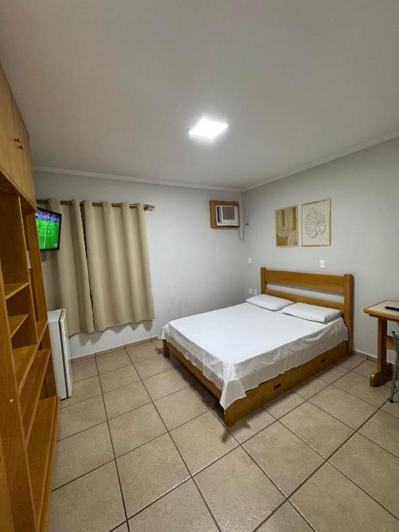 a bedroom with a bed and a television in it at Bica Conveniência e Hotel in Urupês