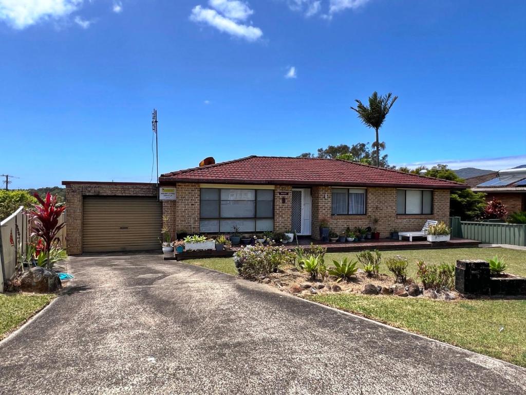 a brick house with a garage and a palm tree at Rocky in South West Rocks