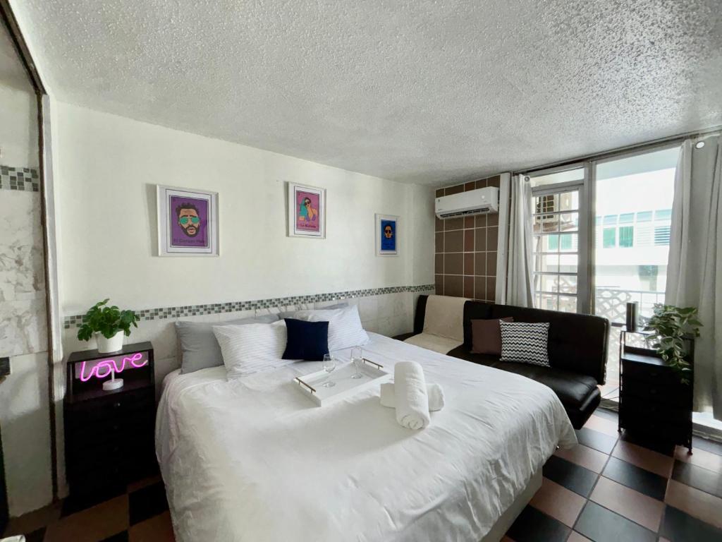 a bedroom with a large white bed and a couch at Isla Verde Modern Apartment with Pool in San Juan