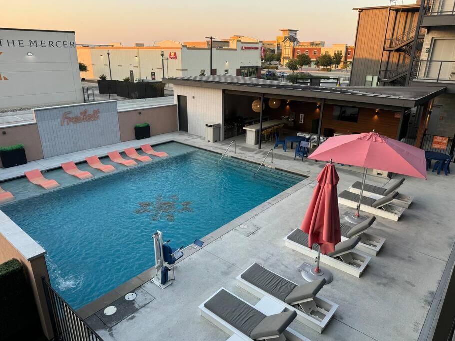 einem Pool mit Stühlen und einem Sonnenschirm auf einem Gebäude in der Unterkunft Freiheit Loft offers a Lush Couples Getaway near Gruene in New Braunfels